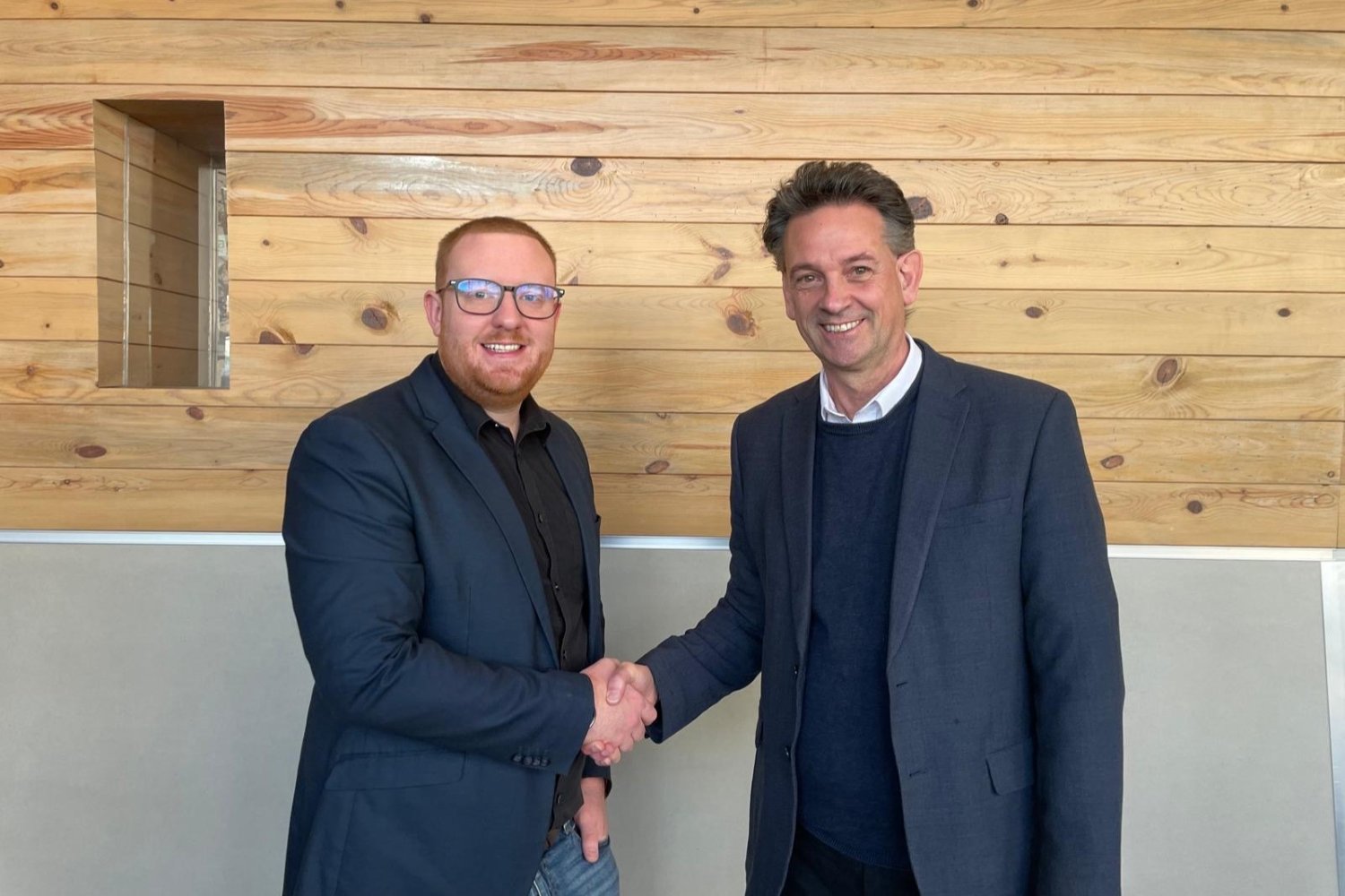Two men shaking hands and smiling at the camera